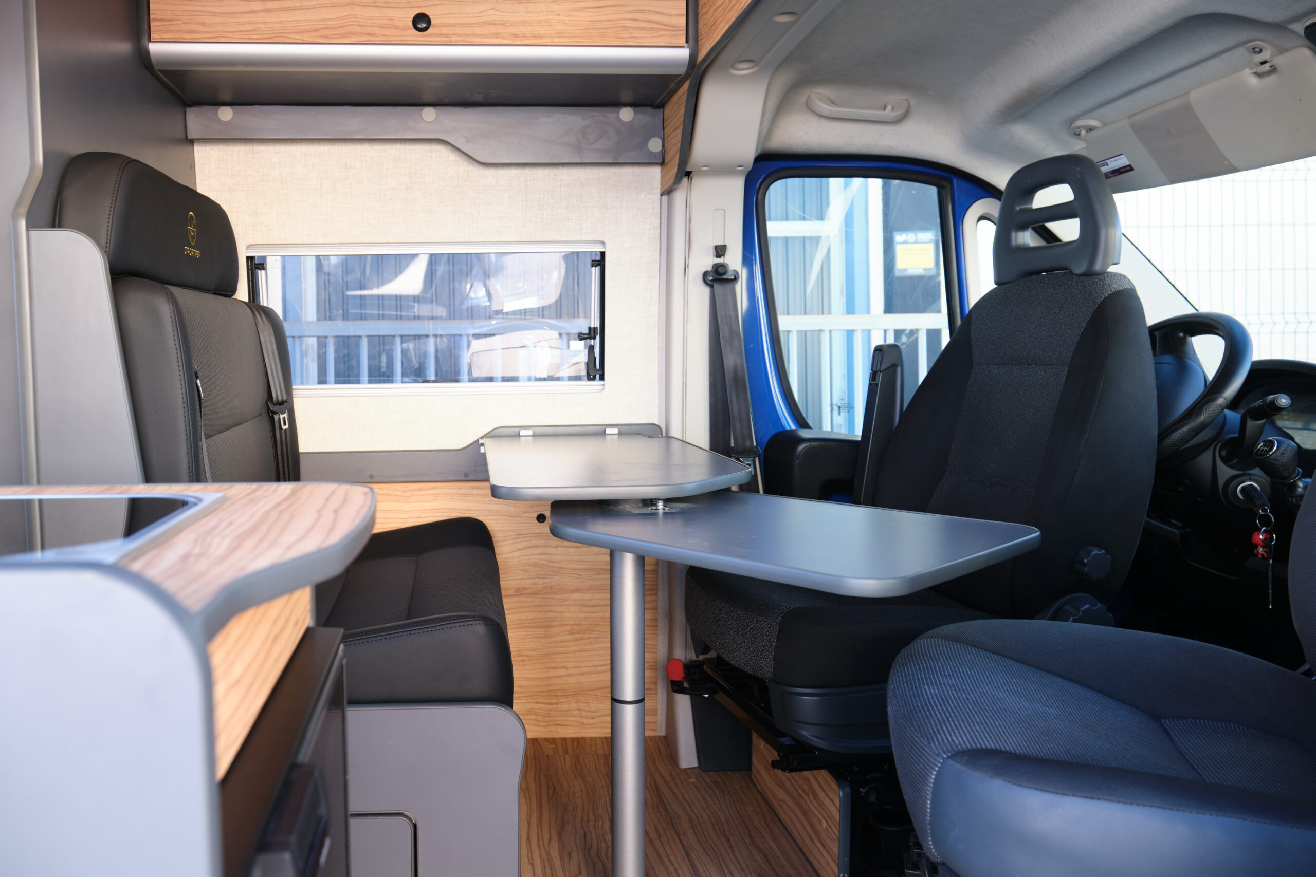 Salón con mesa asientos y asientos giratorios de la camper compact